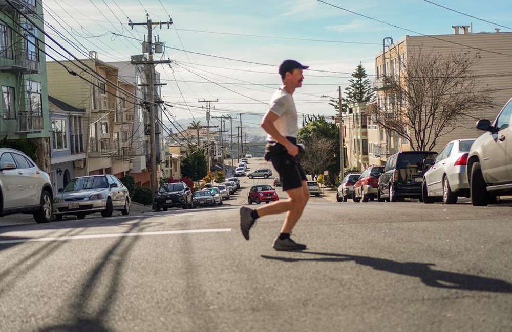 A runner alone on an open road at sunrise, mountains in the distance — her own route, no start line